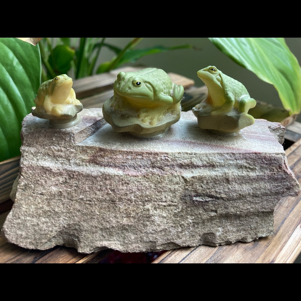 Three frogs on a rock. Garden ornament.